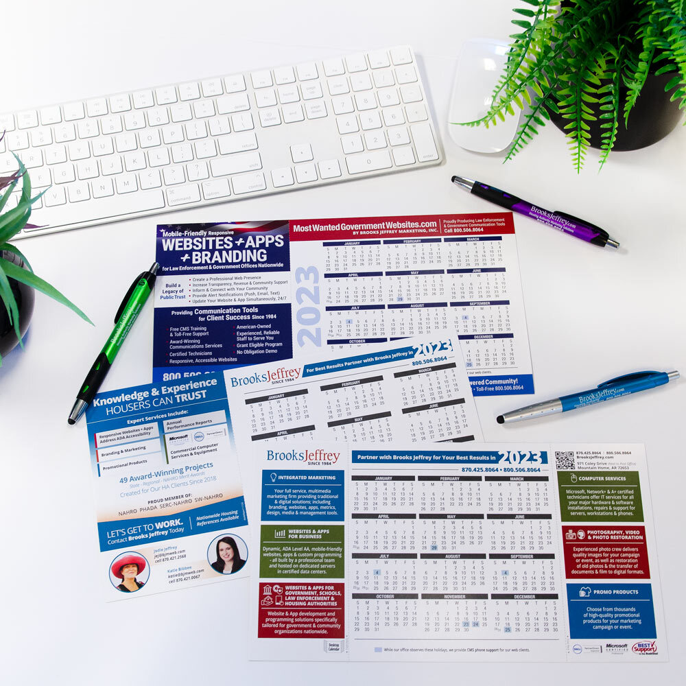 Three 2023 Calendars surrounded by pens and a keyboard.