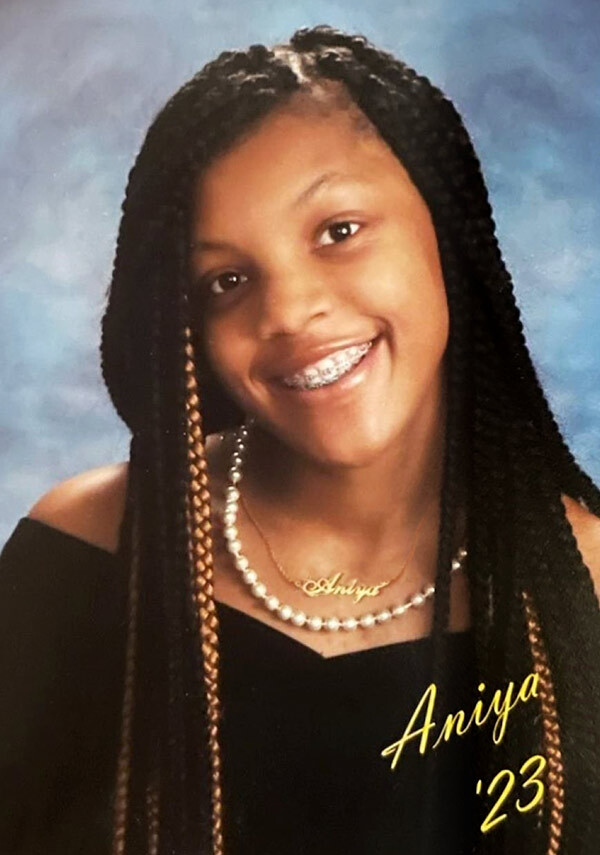 Aniya Rogers school portrait, head tilted, black off the shoulder top, smiling at camera