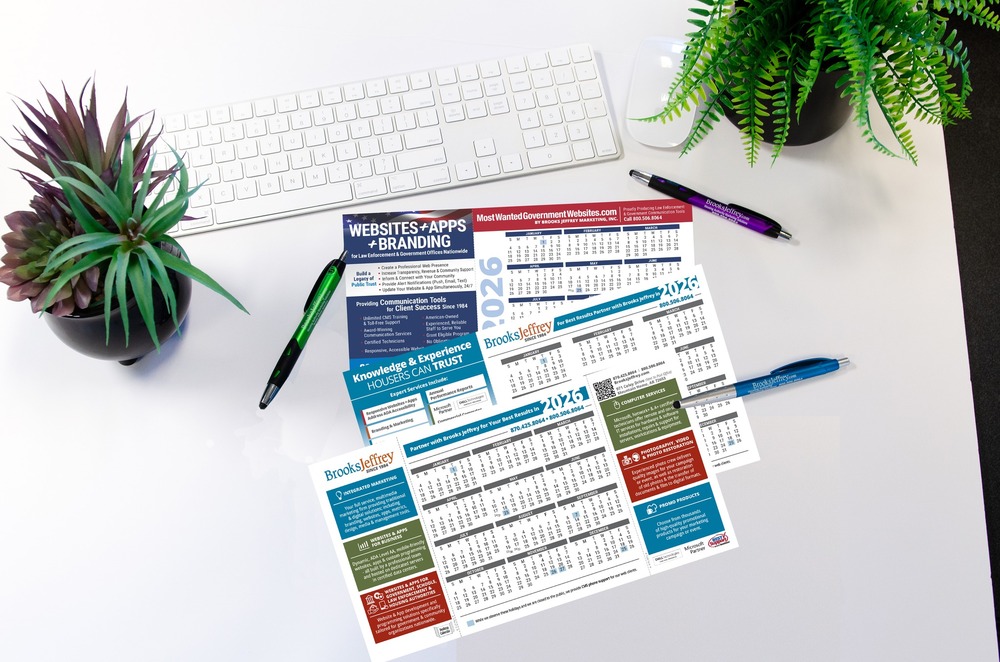 Three 2026 Calendar's with three pens, two plants and a keyboard around them. 