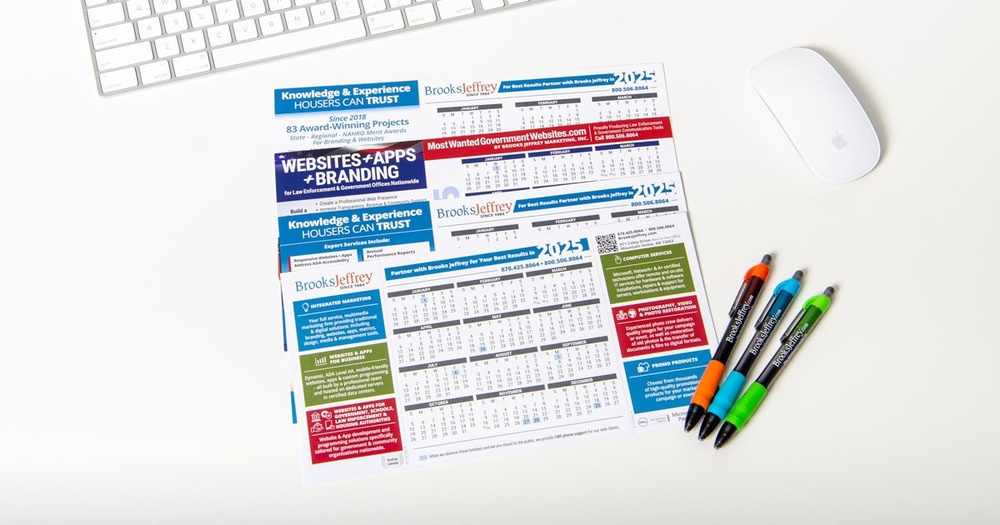Three 2025 Calendars with three pens next to them, a computer mouse, and a keyboard.