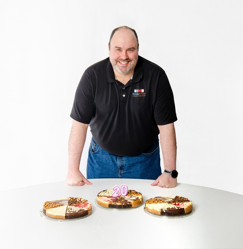 Brian smiling in front of three cheesecakes on a table.