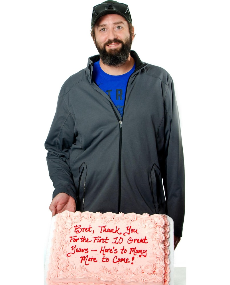 Bret smiling with a cake that says Bret, thank you for the first 10 great years. Here's to many more to come!