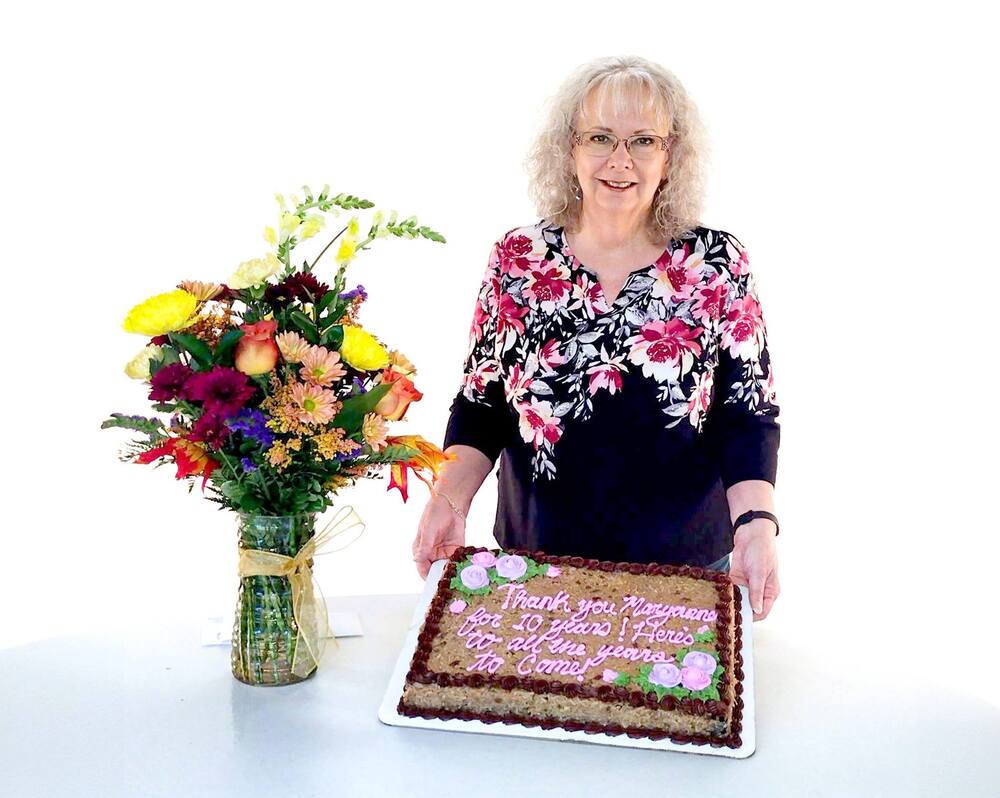Maryanne holding a cake that says Thank you Maryanne for 10 Years! Here to all the years to come!